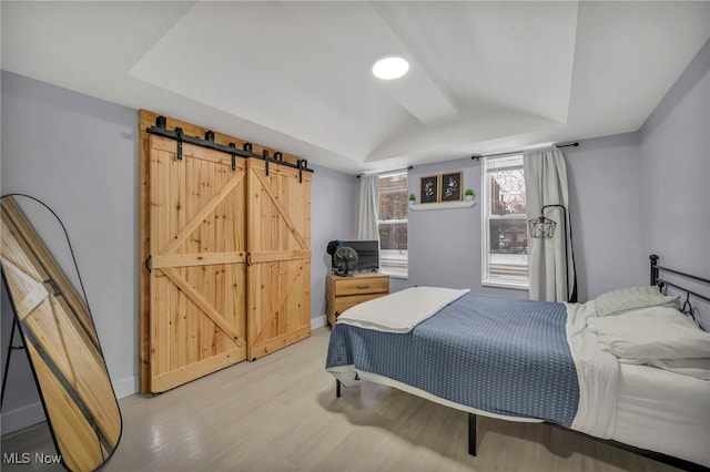 bedroom with a barn door and a tray ceiling