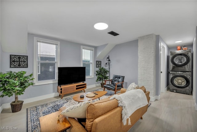 living room with light hardwood / wood-style flooring and stacked washing maching and dryer