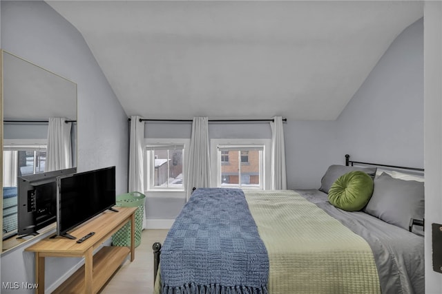 bedroom featuring light hardwood / wood-style flooring, multiple windows, and vaulted ceiling