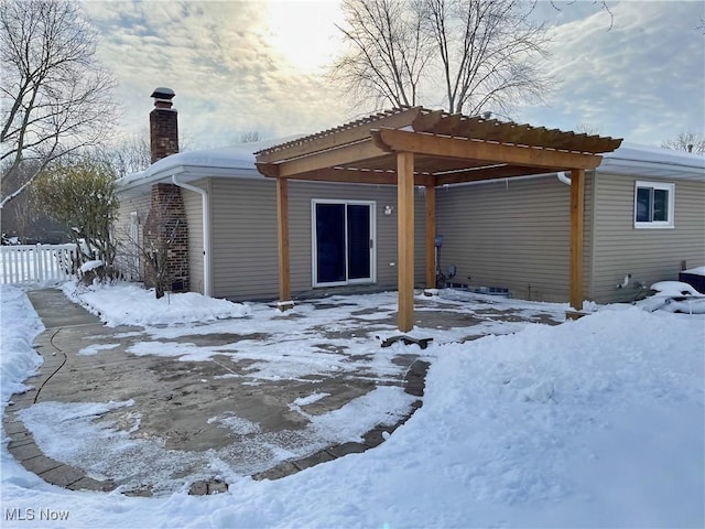 snow covered house featuring a pergola