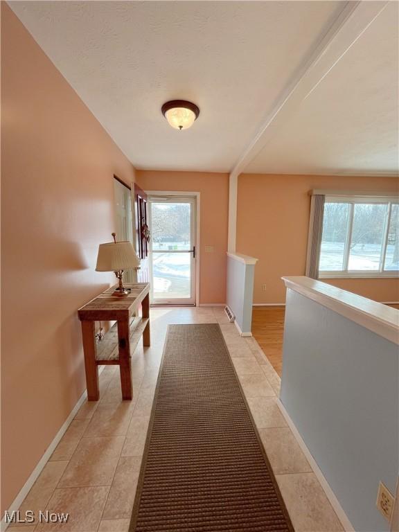 hall featuring a wealth of natural light and light tile patterned flooring