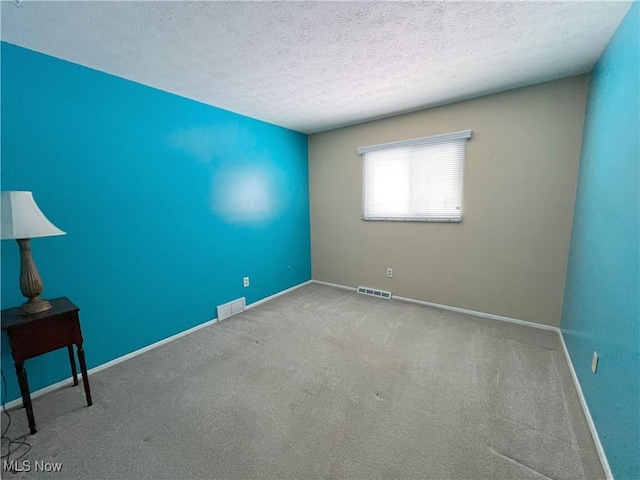 carpeted empty room featuring a textured ceiling