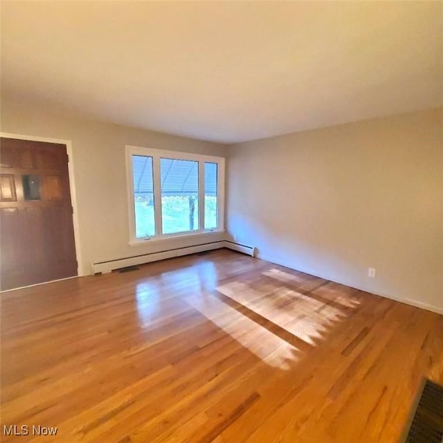 spare room featuring hardwood / wood-style flooring and baseboard heating