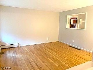 empty room with baseboard heating and hardwood / wood-style floors