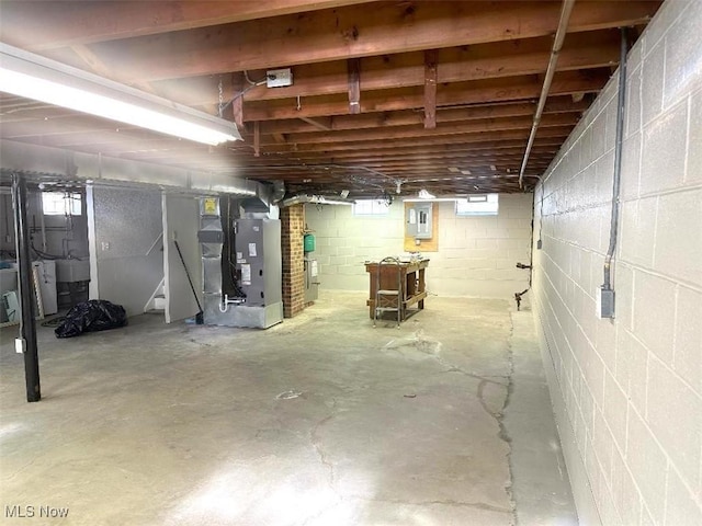 basement featuring heating unit, a healthy amount of sunlight, and electric panel