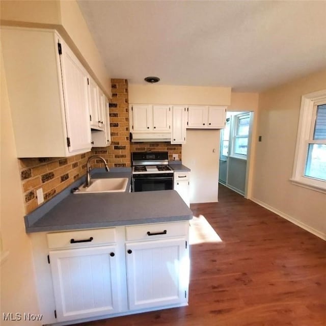 kitchen featuring tasteful backsplash, stove, sink, white cabinets, and dark hardwood / wood-style flooring