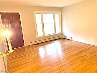 unfurnished room with light wood-type flooring and baseboard heating