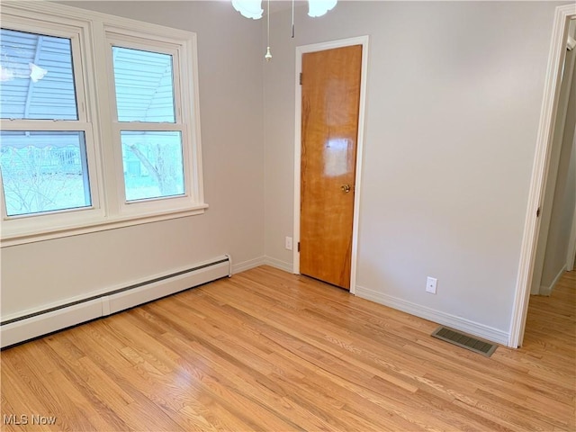 unfurnished bedroom featuring a baseboard heating unit, light wood-type flooring, and multiple windows