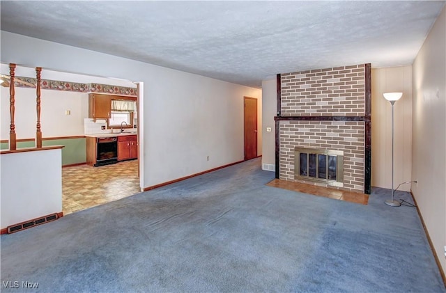 unfurnished living room with a textured ceiling, light colored carpet, sink, a fireplace, and wine cooler