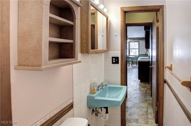 bathroom featuring built in shelves, sink, and tile walls