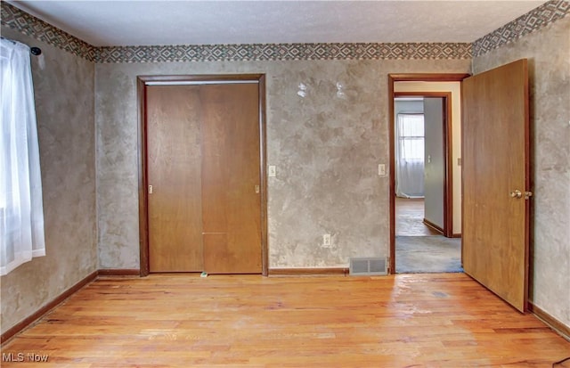 unfurnished bedroom featuring light wood-type flooring and a closet