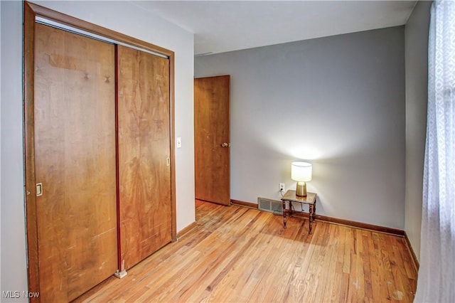 unfurnished bedroom with light wood-type flooring and a closet