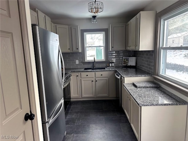 kitchen featuring sink, hanging light fixtures, stainless steel fridge, electric stove, and decorative backsplash