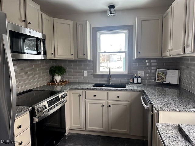 kitchen with light stone countertops, stainless steel appliances, white cabinetry, and sink