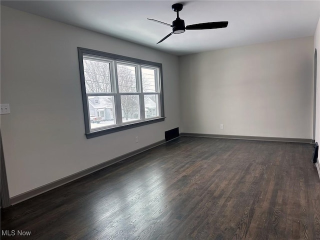 empty room with ceiling fan and dark hardwood / wood-style flooring