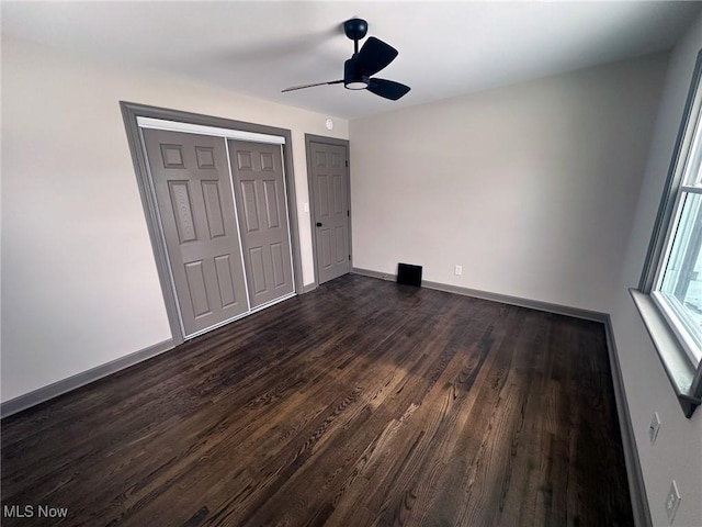 unfurnished bedroom with ceiling fan and dark wood-type flooring