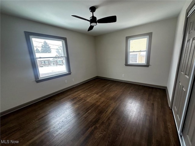 unfurnished bedroom featuring multiple windows, dark hardwood / wood-style flooring, a closet, and ceiling fan