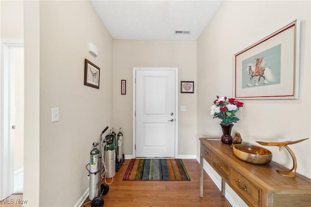 doorway to outside with a textured ceiling and hardwood / wood-style floors