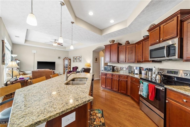 kitchen featuring stainless steel appliances, sink, a raised ceiling, ceiling fan, and pendant lighting