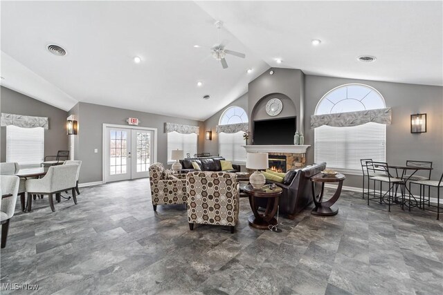 living room with ceiling fan, french doors, a stone fireplace, and lofted ceiling