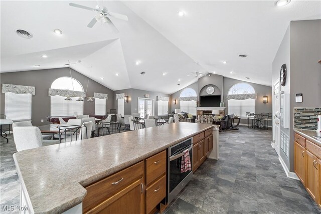 kitchen with lofted ceiling, a kitchen island, and ceiling fan