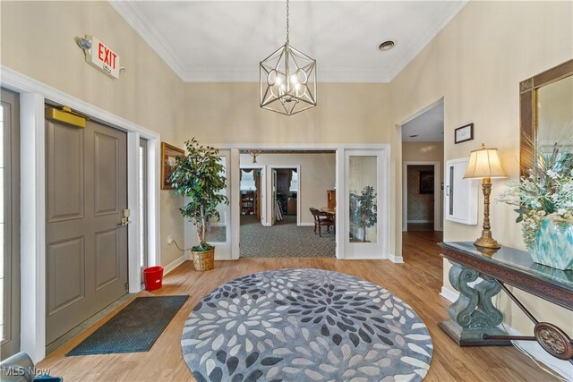 entrance foyer with a notable chandelier, light wood-type flooring, french doors, and ornamental molding