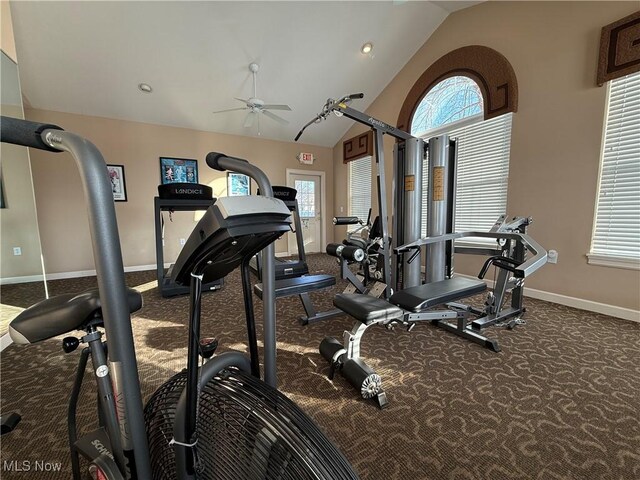 exercise room featuring ceiling fan, a healthy amount of sunlight, vaulted ceiling, and dark carpet