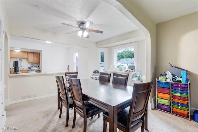 carpeted dining room featuring a textured ceiling and ceiling fan