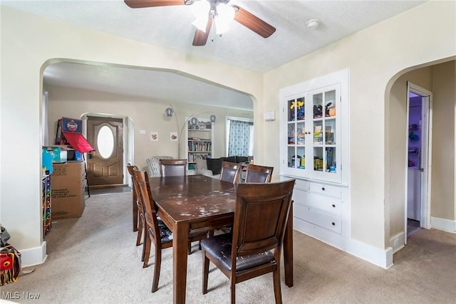 dining space featuring a textured ceiling, ceiling fan, and light carpet