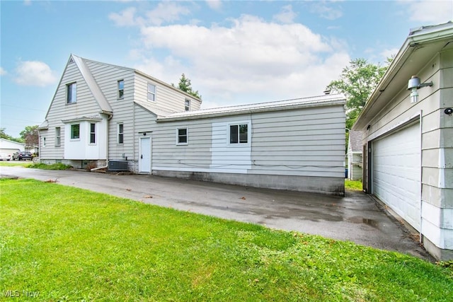 back of property featuring a lawn and a garage