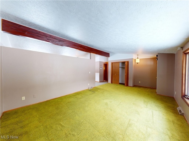 carpeted spare room featuring a textured ceiling and beam ceiling