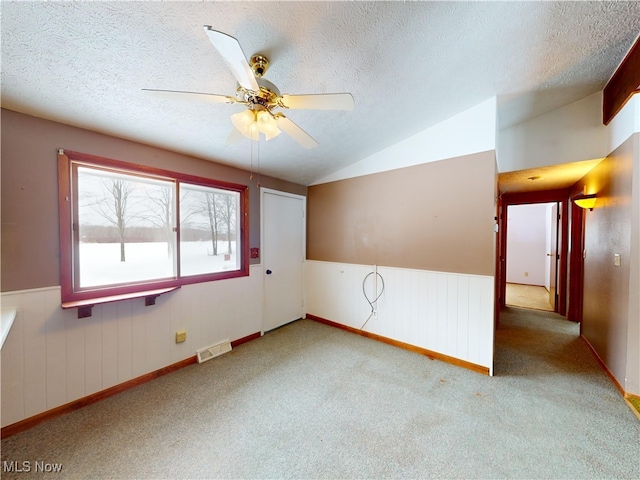 carpeted empty room with lofted ceiling, a textured ceiling, and ceiling fan