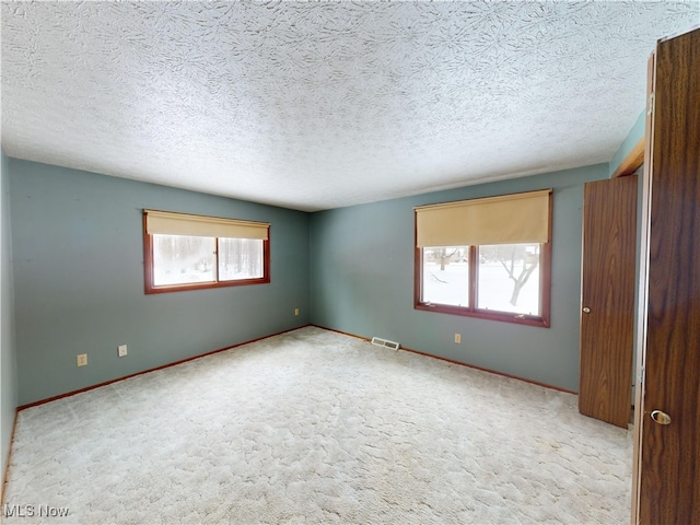 carpeted spare room featuring a textured ceiling