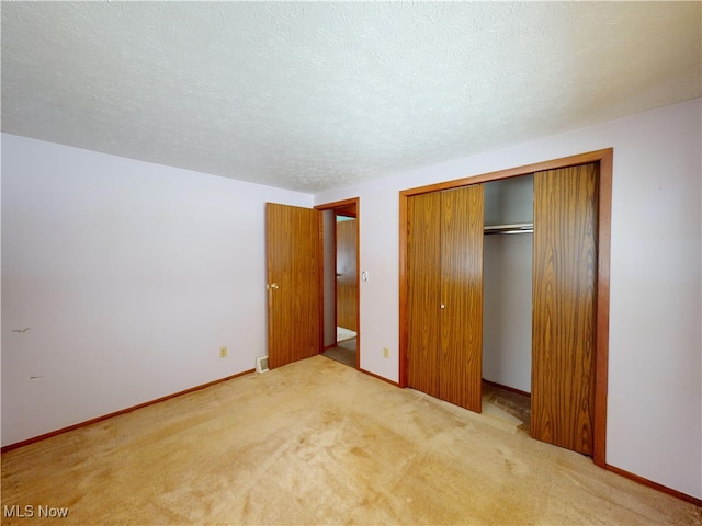 unfurnished bedroom featuring a textured ceiling, light colored carpet, and a closet