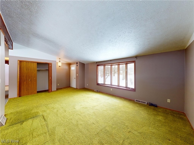 spare room featuring a textured ceiling, vaulted ceiling, and carpet floors