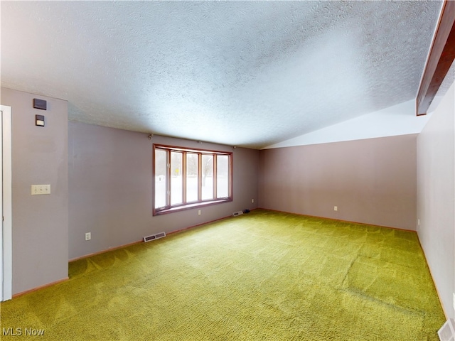 carpeted spare room with a textured ceiling and vaulted ceiling