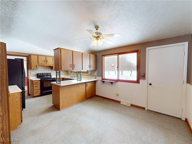 kitchen featuring sink, ceiling fan, kitchen peninsula, decorative backsplash, and black appliances