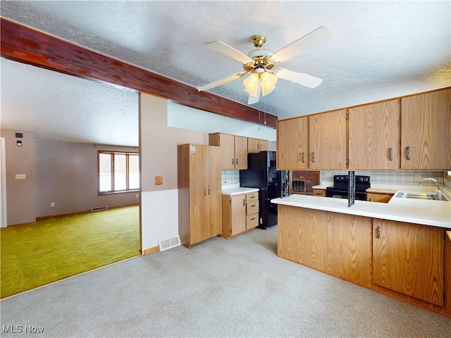 kitchen with sink, a textured ceiling, light carpet, kitchen peninsula, and black appliances