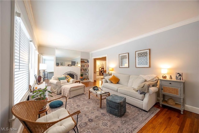 living room featuring dark hardwood / wood-style floors, a brick fireplace, crown molding, and built in shelves