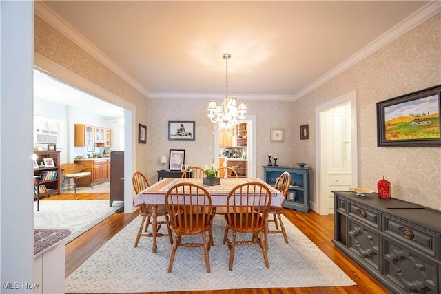 dining space featuring an inviting chandelier, light wood-type flooring, and crown molding