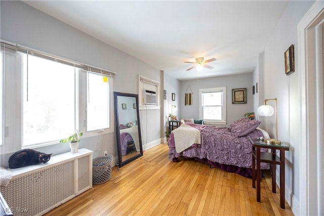 bedroom with radiator, a wall mounted AC, ceiling fan, and light hardwood / wood-style flooring