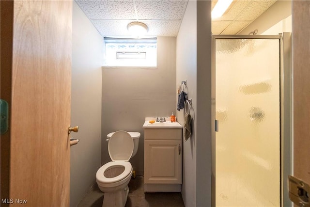 bathroom featuring a paneled ceiling, a shower with door, vanity, and toilet