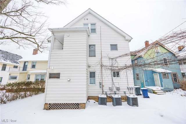 snow covered back of property with central AC