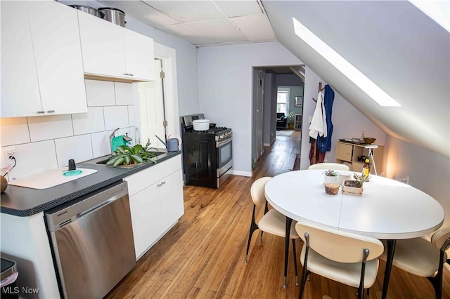 kitchen featuring appliances with stainless steel finishes, light wood-type flooring, white cabinets, and tasteful backsplash