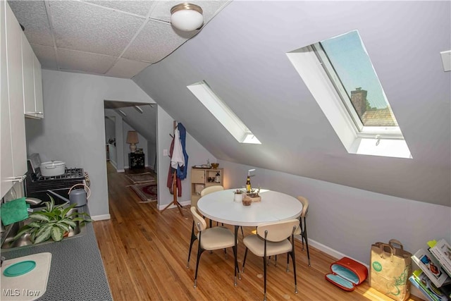 additional living space with vaulted ceiling with skylight and wood-type flooring