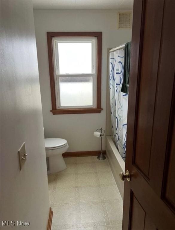 bathroom featuring toilet and shower / bath combo with shower curtain