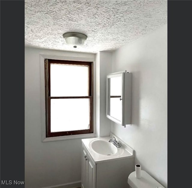 bathroom featuring a textured ceiling, vanity, and toilet