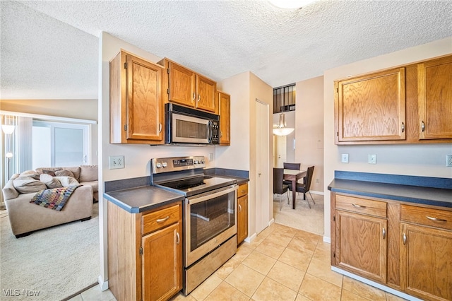 kitchen with vaulted ceiling, stainless steel appliances, a textured ceiling, and light tile patterned flooring