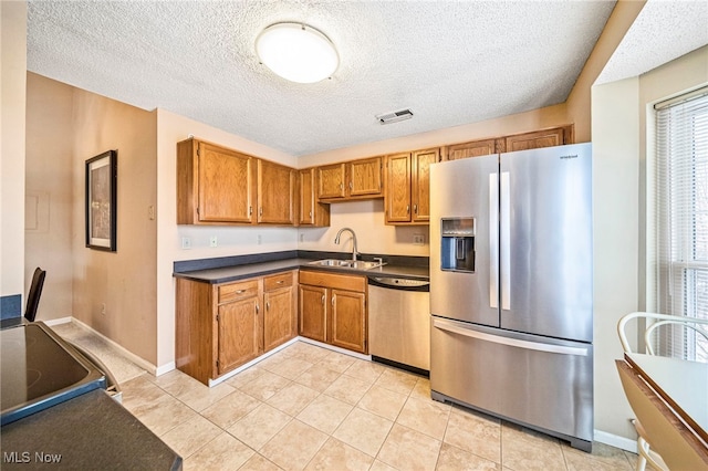 kitchen with plenty of natural light, stainless steel appliances, a textured ceiling, and sink