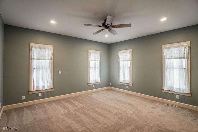 unfurnished room featuring light colored carpet, ceiling fan, and a healthy amount of sunlight